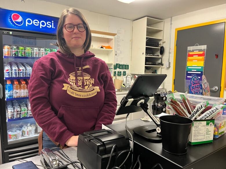 A woman standing behind a canteen counter. 