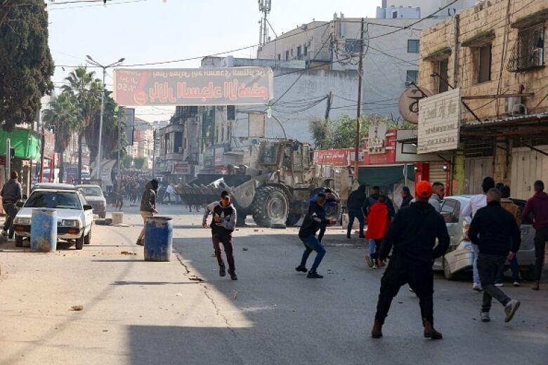 Young men throw rocks at a column of officers in the distance.