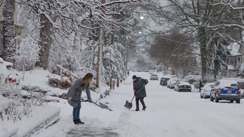 People shovel snow during a winter storm in Toronto on Wednesday, Jan. 25, 2022 