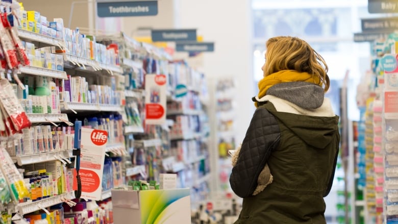 Woman stands in aisle at a Shoppers Drug Mart