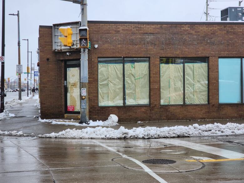 A brick storefront with windows covered in paper.