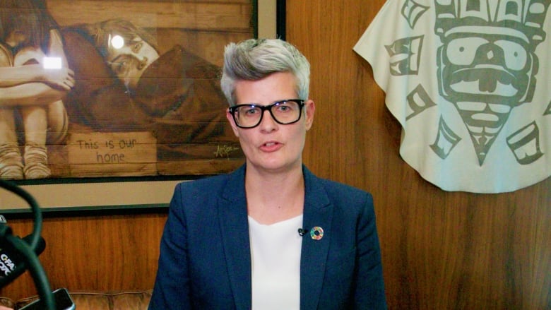 A woman with short grey hair stands at a podium.