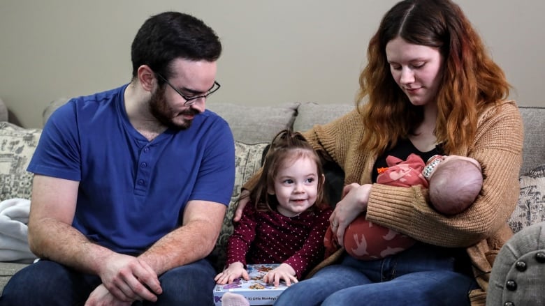 Rachel Dempster holds baby Amadea in her arms as daughter Adaline and husband Braeden sit beside her on the couch of their Drayton Valley, Alberta home.