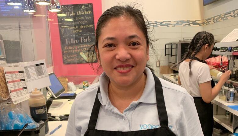 A woman stands in the kitchen of Yogen Fruz. 