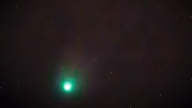 A glowing green spot in a sky specked with small stars