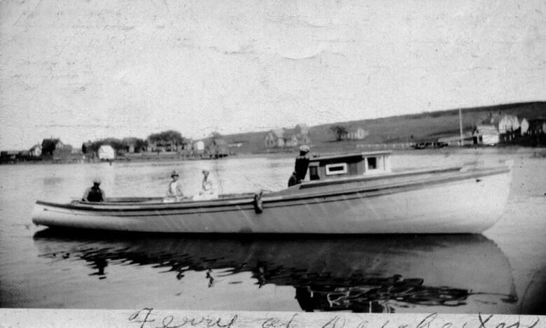 black and white photo showing ferry with three passengers, including two women wearing hats