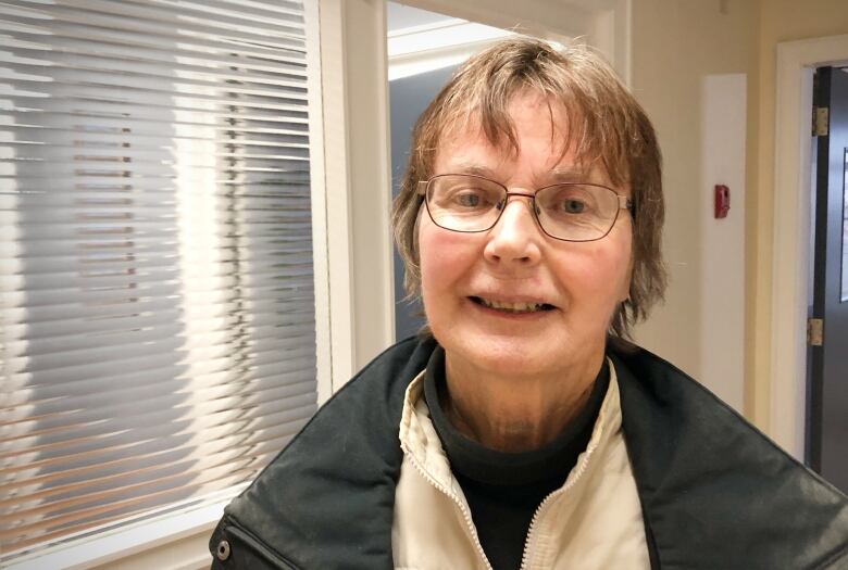 A woman in a hallway faces the camera.