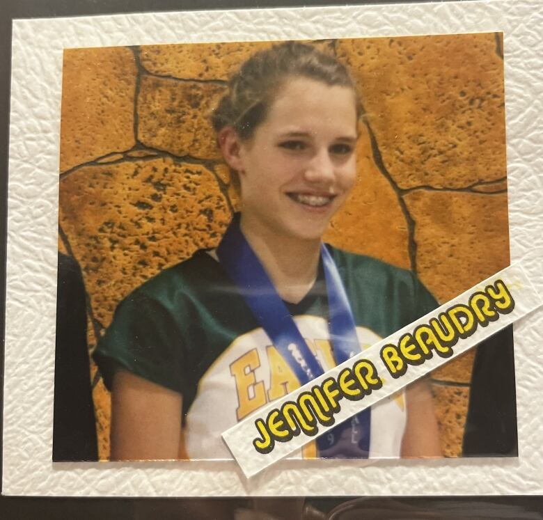 A photo showing a smiling teen wearing an Eagles uniform with a medal around her neck. 