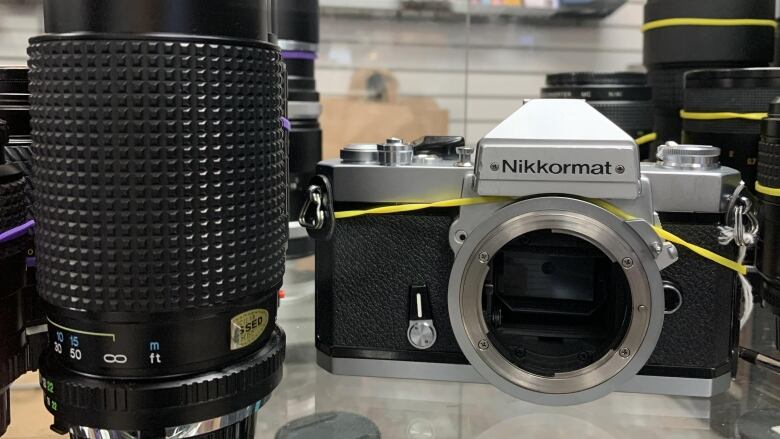 A film camera and a lens are for sale at a store.