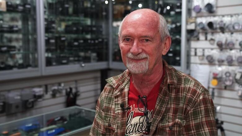 A business owner sits in his camera store.