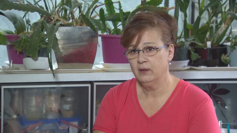 A woman sits for an interview with several plants behind her.