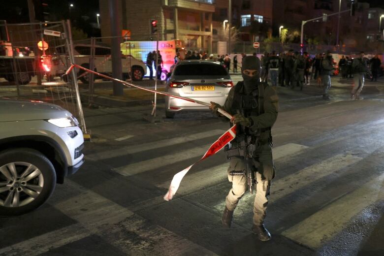 A soldier cordons off an area with police tape.