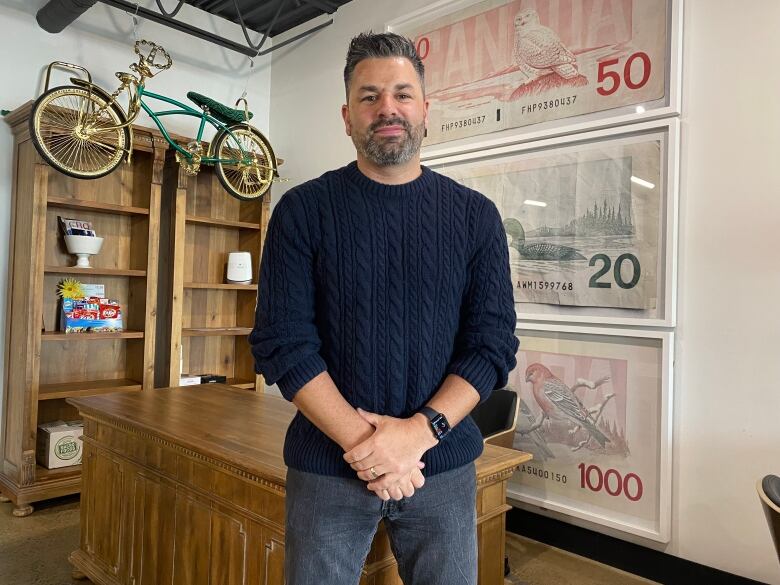 Paul stands in his office. Bike hangs on the ceiling.