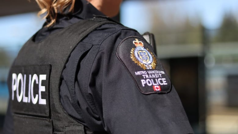 A close up shows the back and shoulder of a female Metro Vancouver Transit Police Officer.