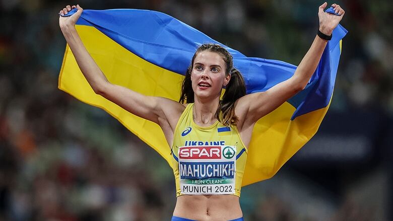 Women's high jumper holds Ukrainian flag behind her back at the 2022 European Championships.