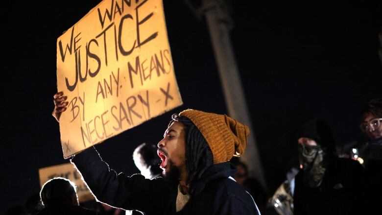 A protester holds up a sign while shouting.