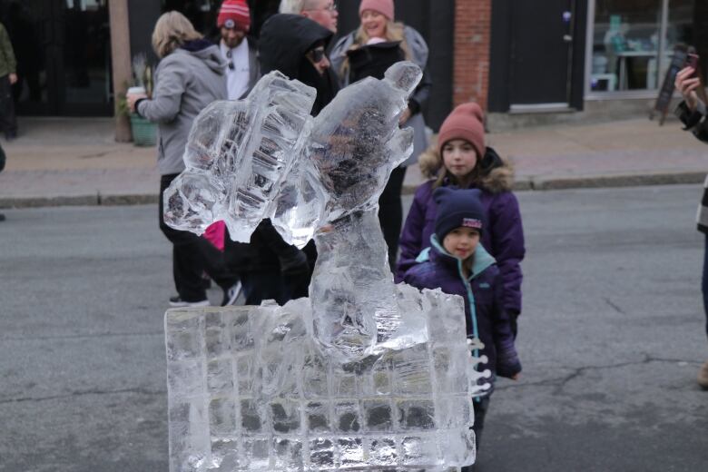 Children look at an ice sculpture of Snoopy on his dog house created by Richard Chiasson.