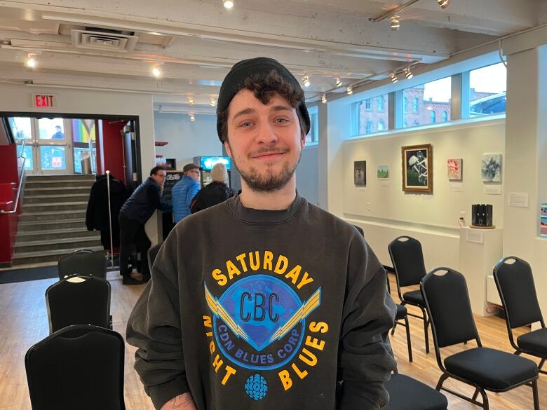 A man standing in an art gallery smiling. 