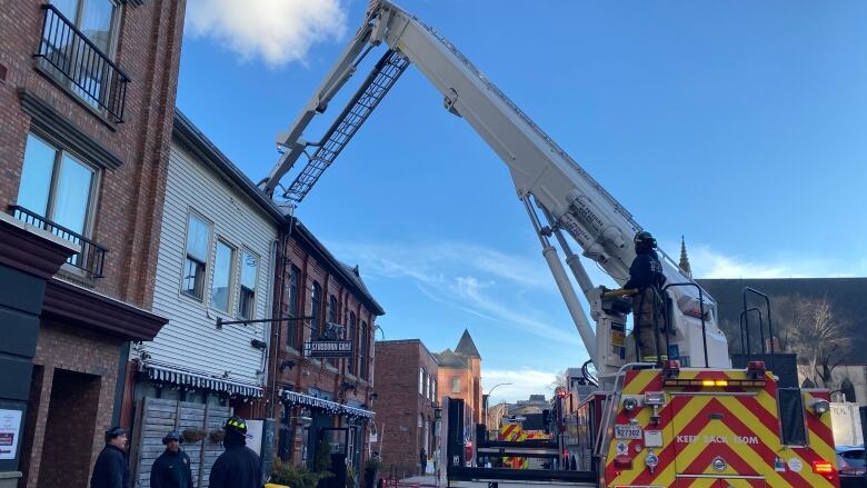 A fire truck with crane is parked in front of a restaurant. 