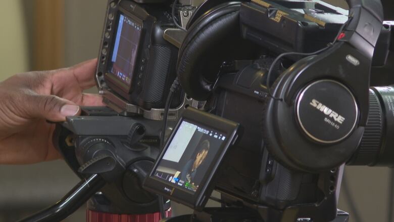 A picture of a man changing settings on a camera while filming a video at the Black Cultural Society of P.E.I. office in Charlottetown.