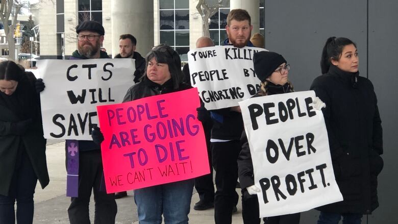 people holding up signs, in support of the CTS coming to downtown Windsor