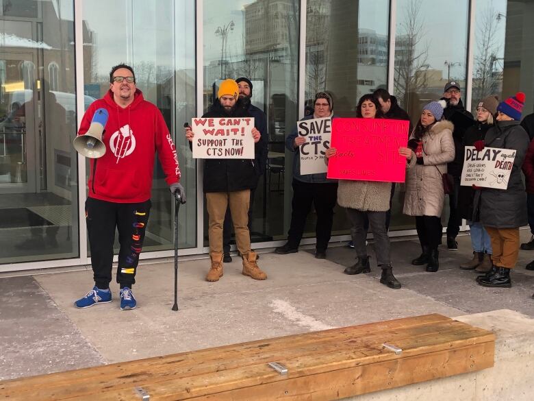 protestors holding signs, one is holding a megaphone