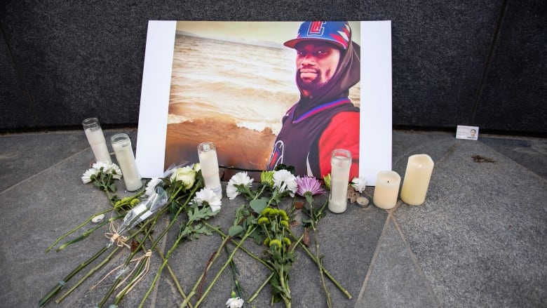 Flowers and candles in front of a photo of a man.