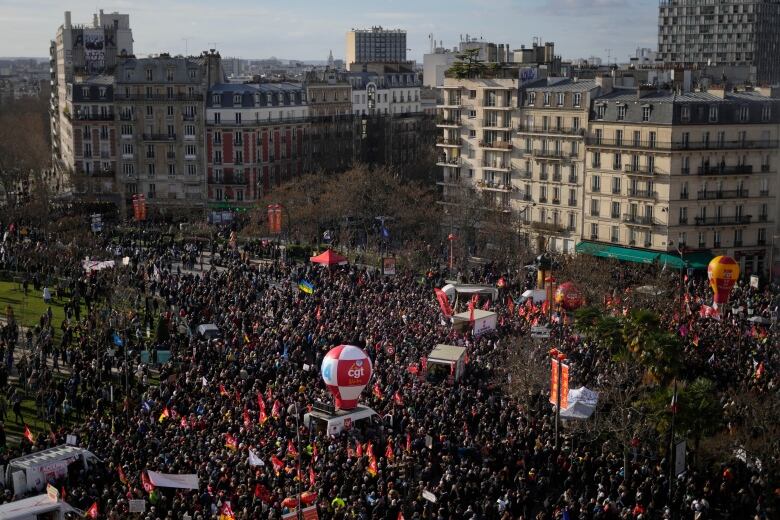 A wide angle photo of protestors demonstrating against pension reform in Paris.