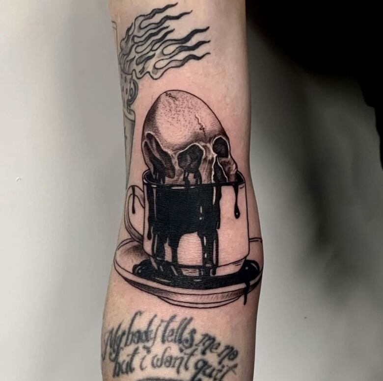 A fresh tattoo featuring a human skull inside a teacup is seen on someone's arm.