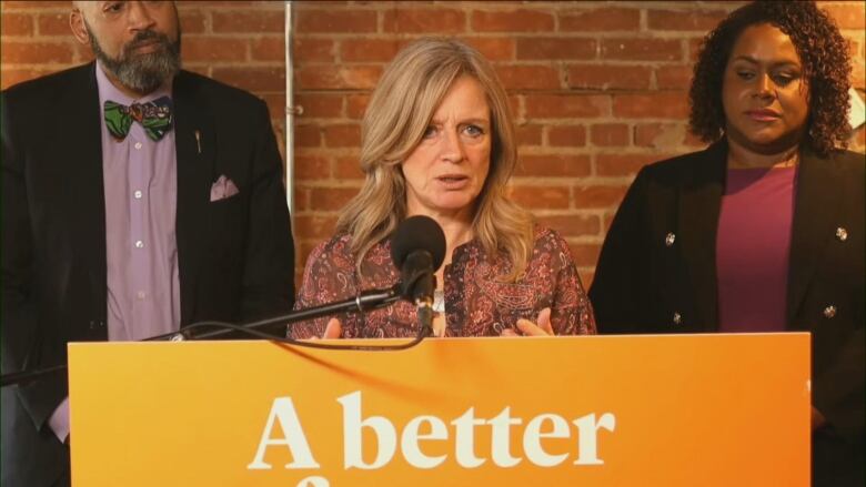 A woman stand behind a podium while speaking.