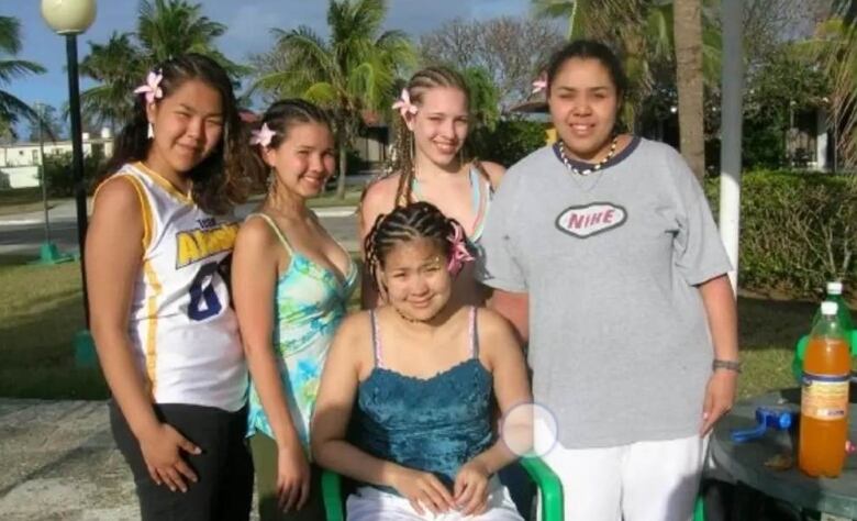 A group of smiling girls and women with flowers in their hair.