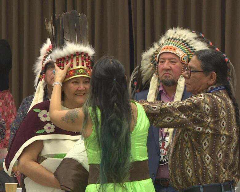 A woman places a headdress on the head of the leader of the Assembly of Manitoba Chiefs.