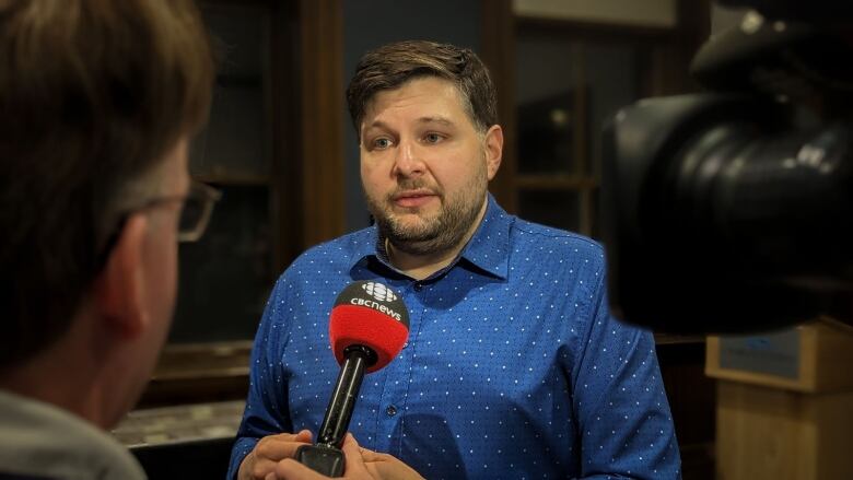 A man talks to a reporter during a TV interview 