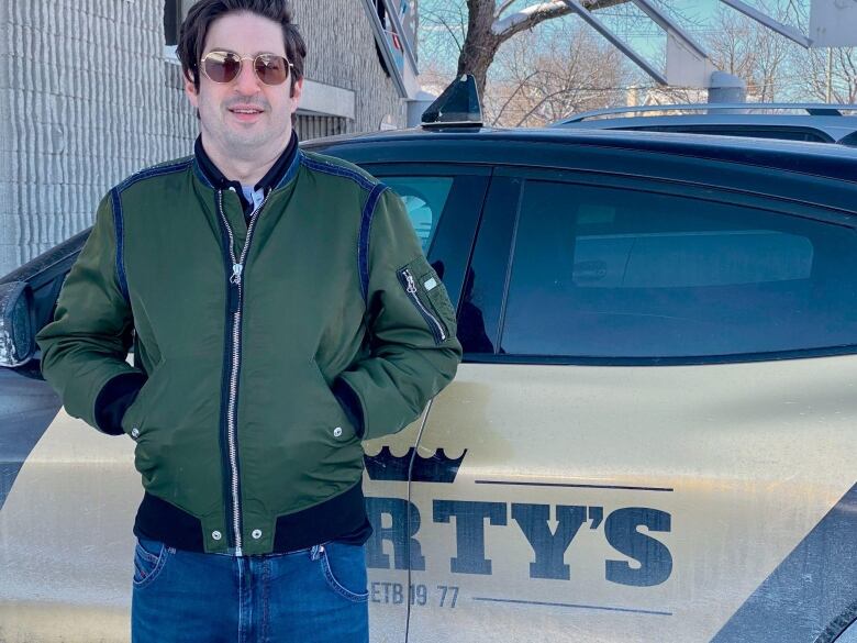 A man leans against a driving school car. 