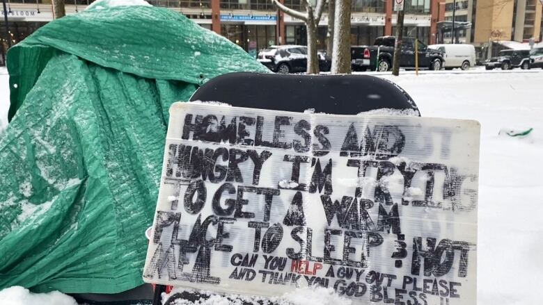 A sign sits near a tent in the snow, it reads, 