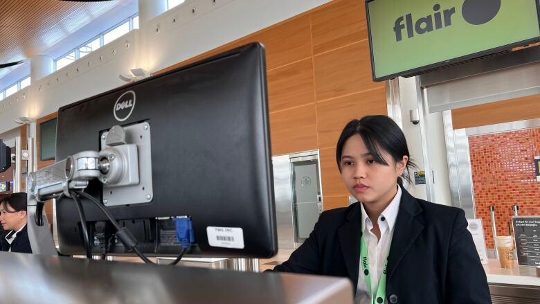 A person works on a computer at an airport desk.