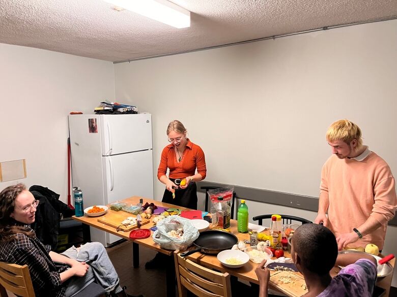 Friends Jade Hongerlood, Grace Poland, Jasmin Cartier and Elizabeth Shevchenko prepare vegetables they found from a dumpster on a kitchen table