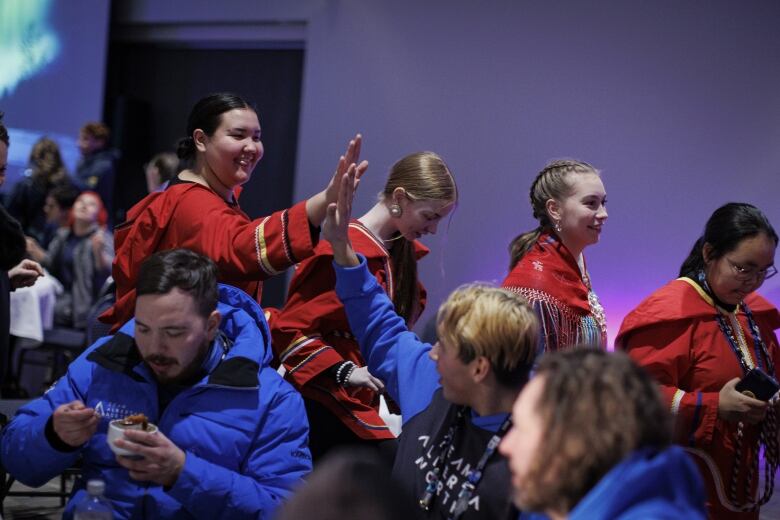 A girl dressed in red high-fives a boy dressed in blue.