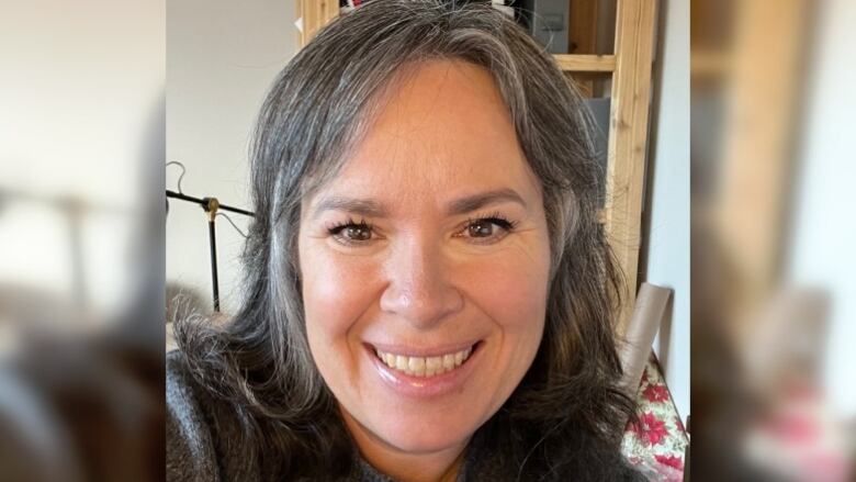 A woman smiling with a bookshelf behind her