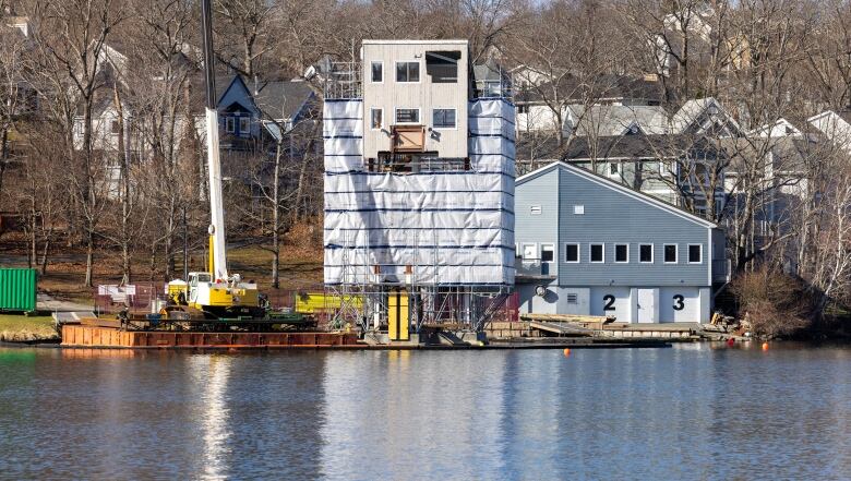 The front view of the tower shows scaffolding around the wooden frame, and a crane to the left side.