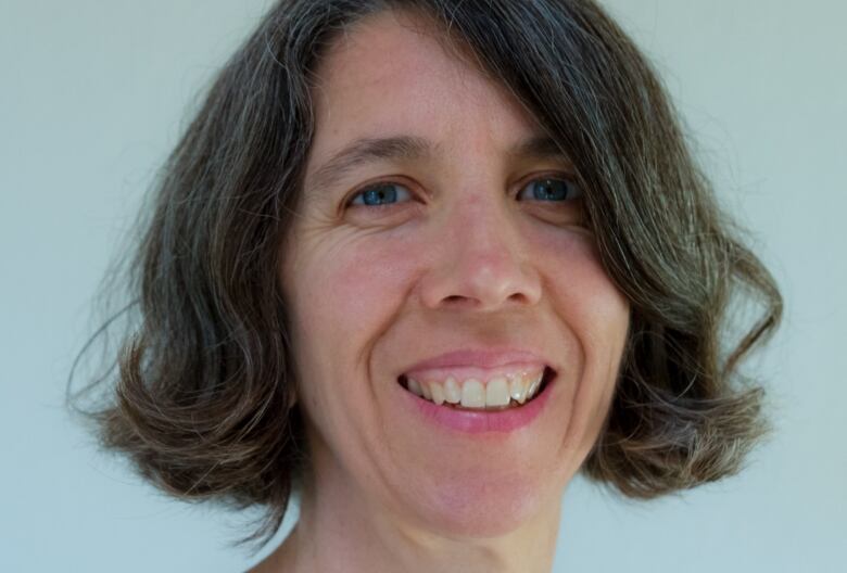 A woman with dark, shoulder-length hair smiles for a portrait. 