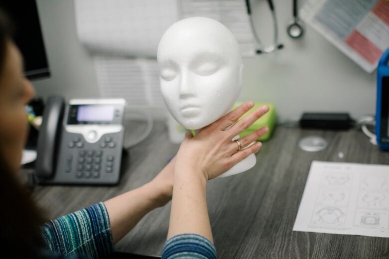 Woman's hand on styrofoam head. 