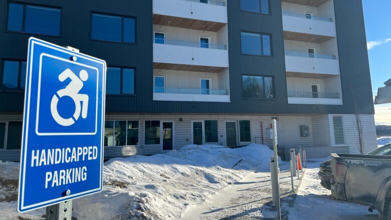 A sign reading 'Handicapped Parking' is seen in front of an apartment complex.