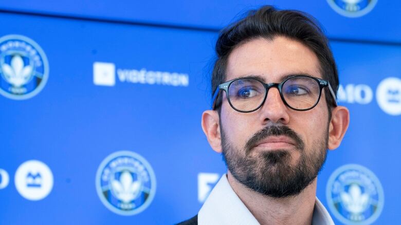 Portrait of a man with dark hair, a close beard and glasses.