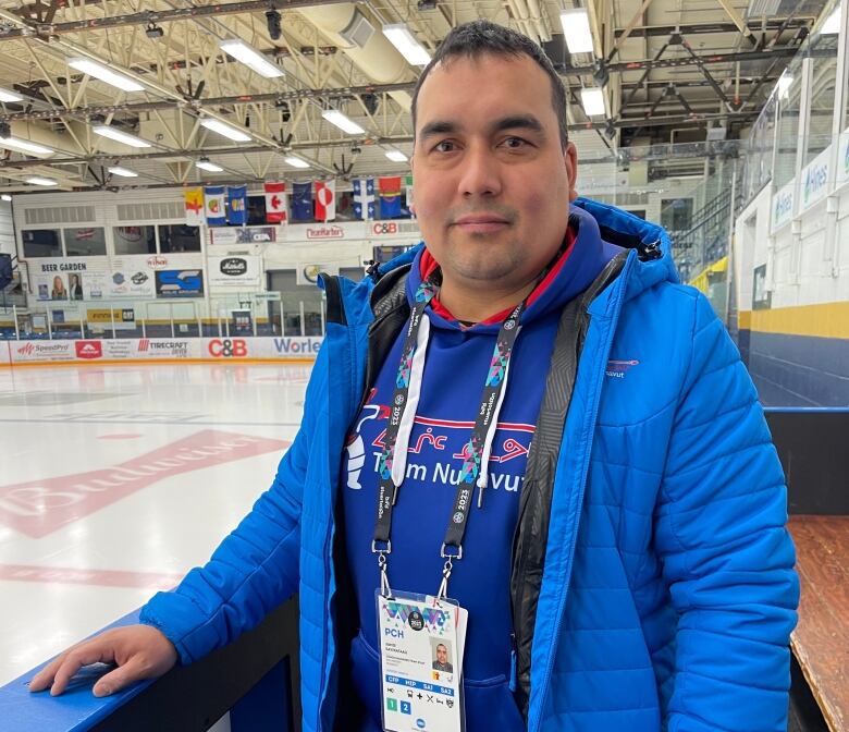 Man in blue at hockey boards.