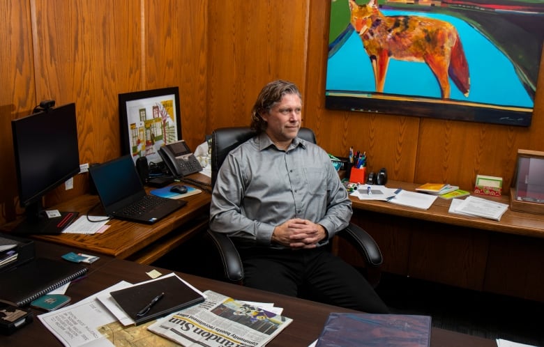 A man sits at a desk looking to the right.