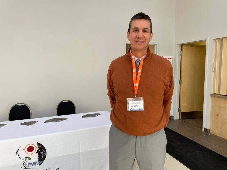 A man stands next to a table at a conference.