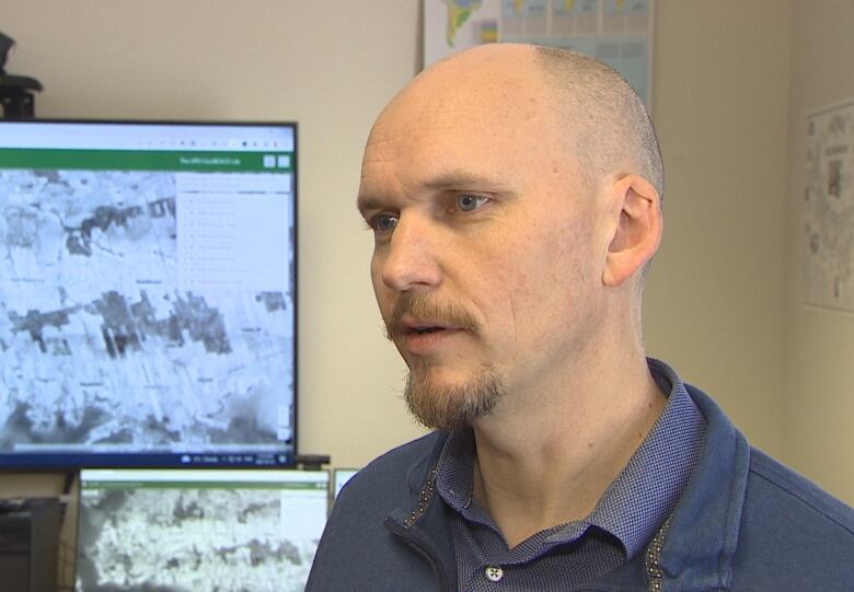 Josh MacFadyen in front of a large computer screen with a map on it.