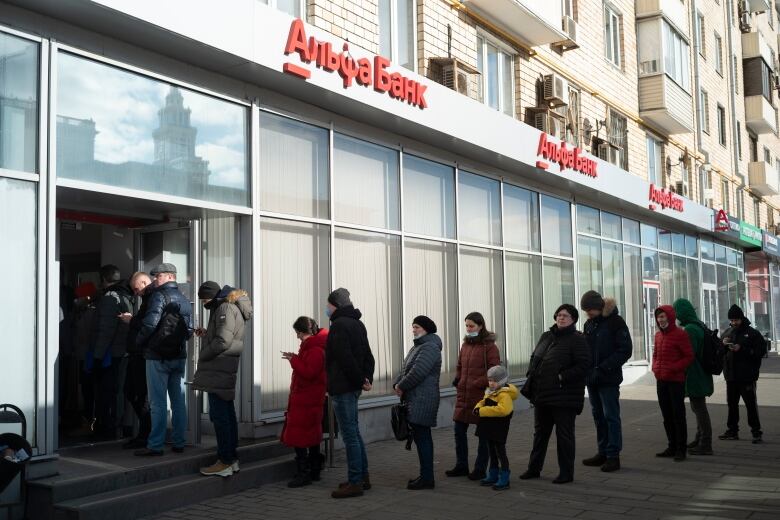 People stand in line to withdraw money from an Alfa Bank ATM in Moscow, Russia on Feb. 27, 2022. Russians flocked to banks and ATMs shortly after Russia launched an attack on Ukraine and the West announced crippling sanctions.