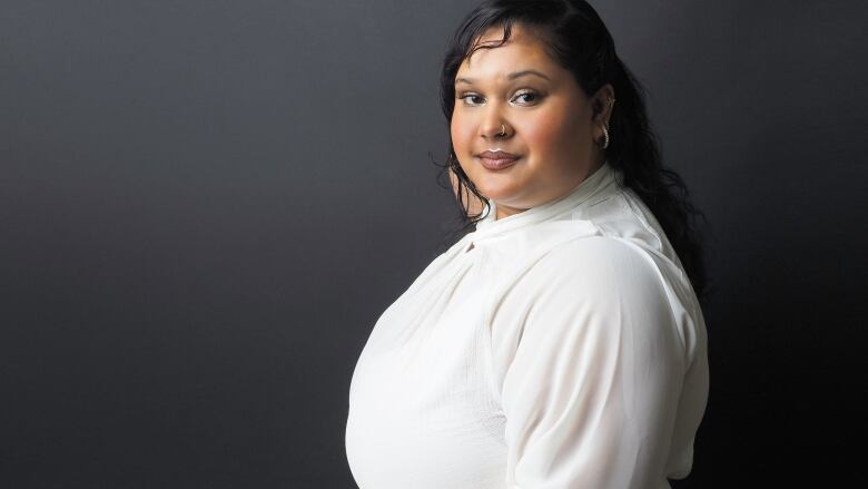 A woman in white blouse looks over her shoulder.